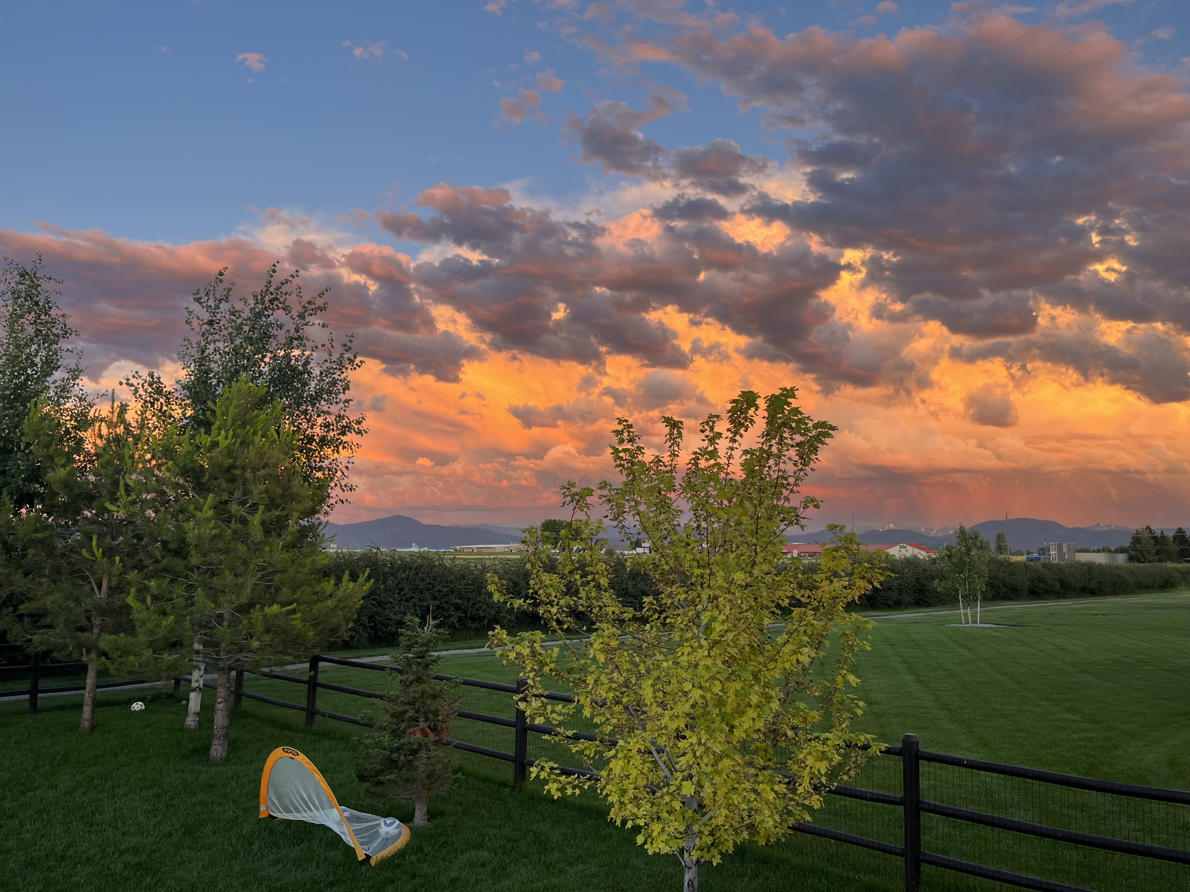 Brown post-and-rail fence at sunset on a Bozeman property